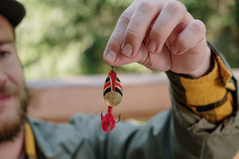 Bearded fisherman showcasing a colorful lure in an outdoor setting.