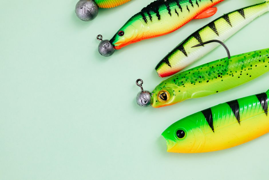 Vibrant assortment of fishing lures with hooks and weights on a pastel green surface.
